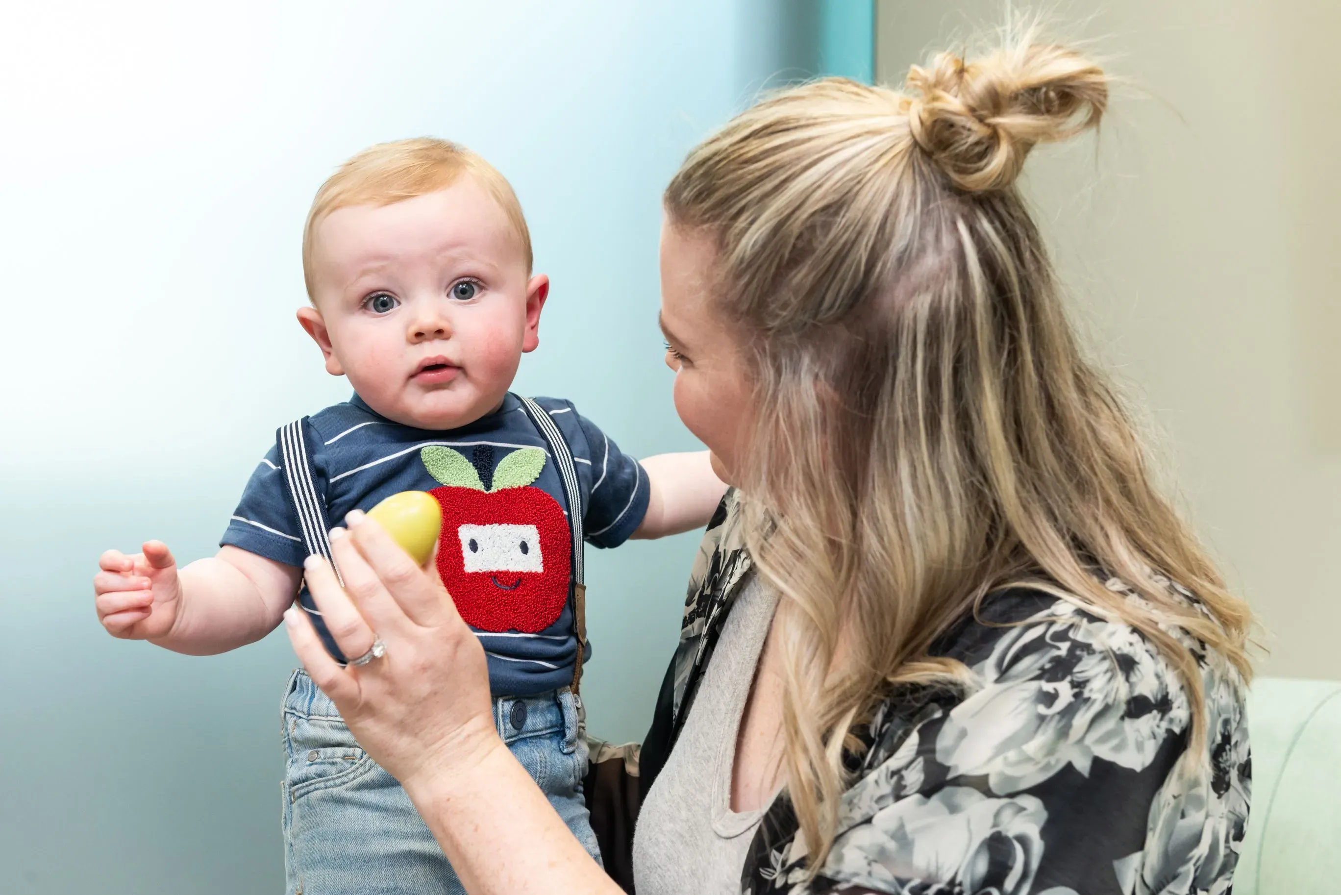 A woman holding a baby. The baby is staring at the camera.