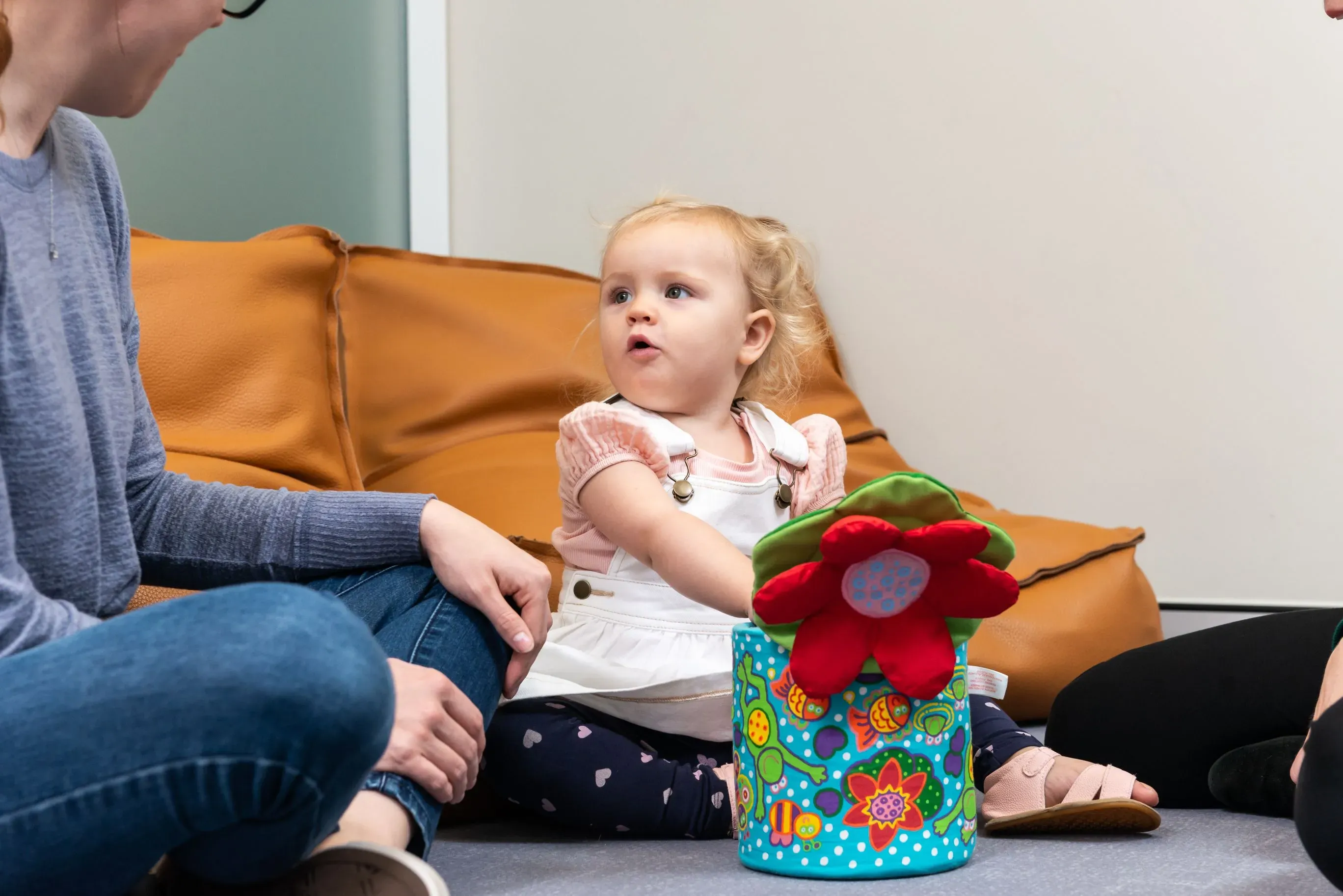A woman and child sitting on the floor. The child is looking up at the woman.