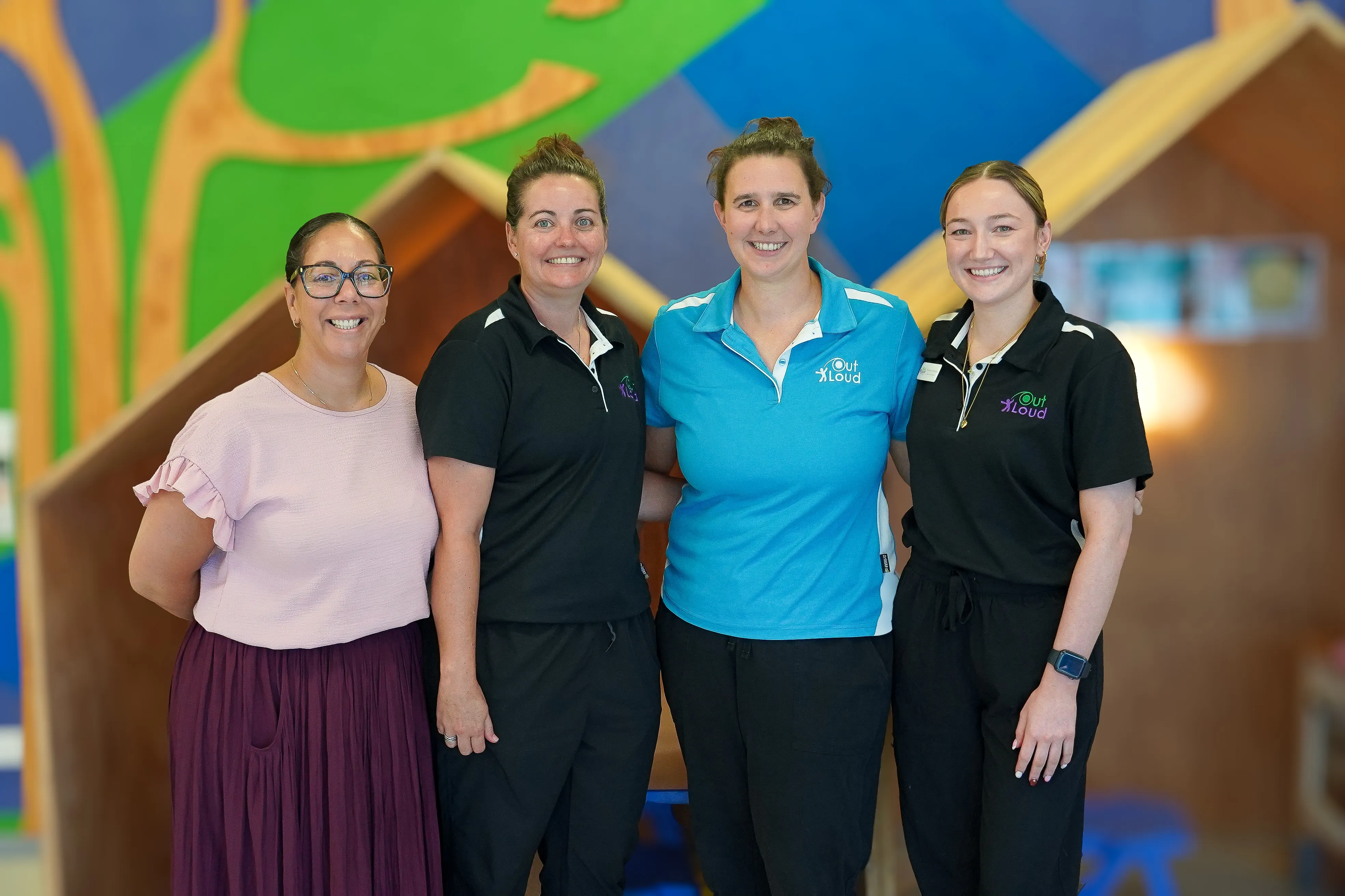Four people standing infront of a colourful wall