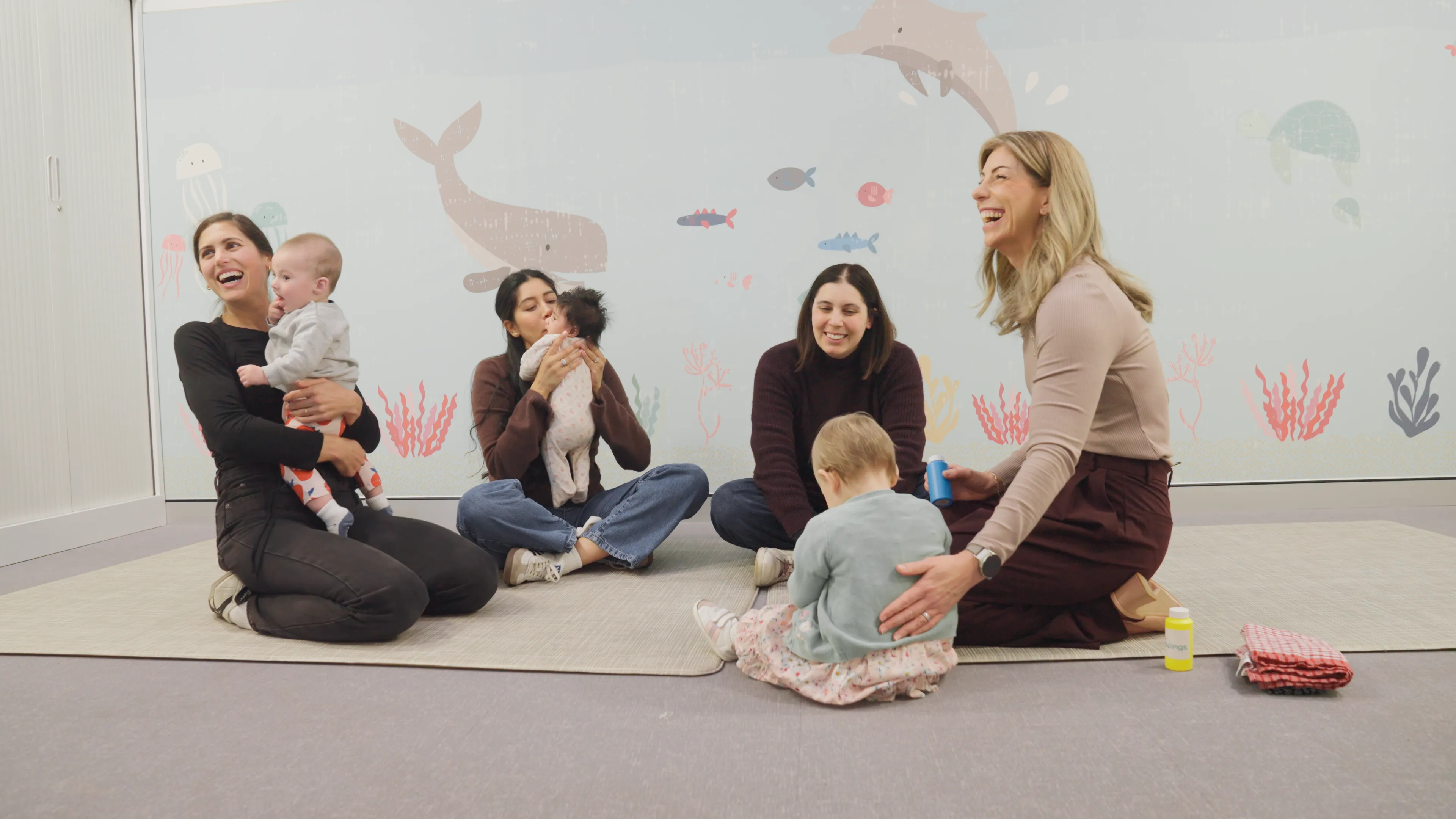 group of women on the floor playing with babies